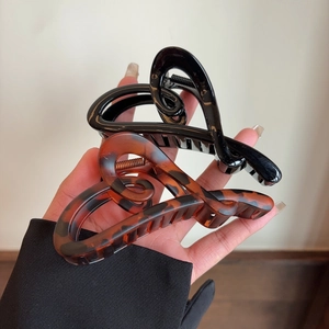 Detail view of large acetate heart hair claws in black and tortoiseshell brown finish