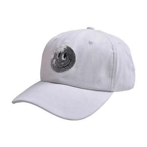 Detail of white washed cotton baseball cap with silver sequin smiley face patch