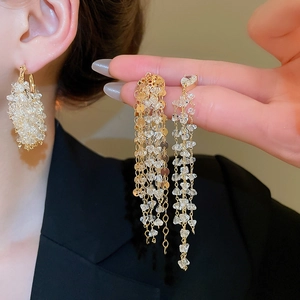 Detail of 18k gold plated tassel earrings with zircon crystals worn on ear