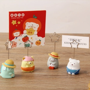 Set of four cute cartoon resin memo holders with star-shaped metal clips on wooden desk