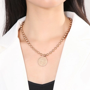 Detail of a gold Saint Benedict medal pendant with embossed figure on a ball chain necklace