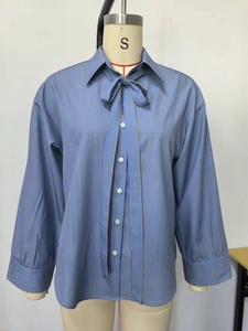 Detail of blue striped long sleeve shirt featuring a decorative bow tie and button front