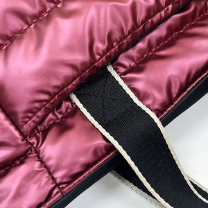 Macro detail of wine red quilted nylon bag with black and white woven strap texture