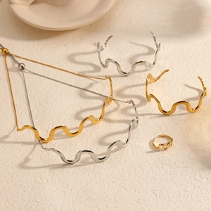 Detail of wavy stainless steel necklace, bracelet and ring set in gold and silver finish