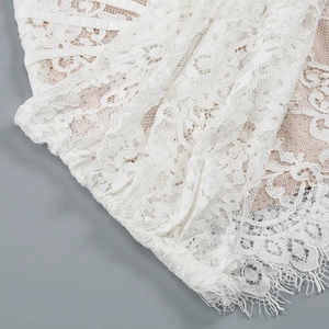 Close-up of white eyelash lace fabric with nude mesh lining on corset dress