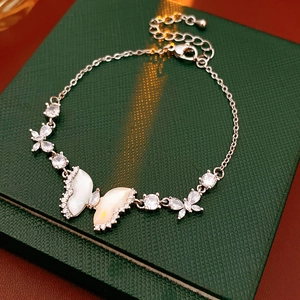 Detail of silver butterfly bracelet with shell inlay and cubic zirconia on green box
