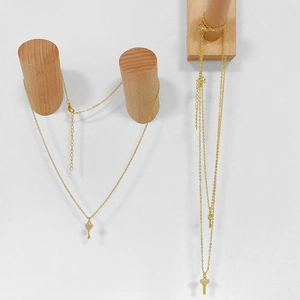 Primer plano de collares dorados con colgantes de llave de corazón en soportes de madera