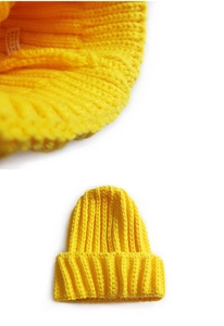 Detail of rib-knit texture and 100% acrylic care label on a yellow beanie hat