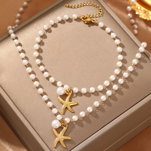 Macro shot of faux pearl jewelry set with starfish pendants on gold necklace and bracelet