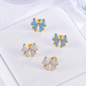 Gros plan sur des boucles d'oreilles nœuds bleu clair et lavande sur support en cuir blanc
