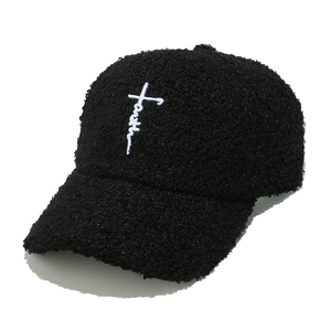 Dettaglio cappello in pile nero con ricamo Faith a croce e consistenza del tessuto morbido