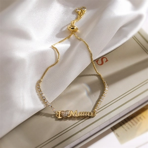 Détail du bracelet doré 'I ❤️ Mama' avec zircons et fermoir ajustable sur du satin