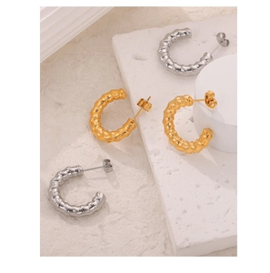 Detailed view of gold and silver C-shaped earrings with bamboo texture on stone