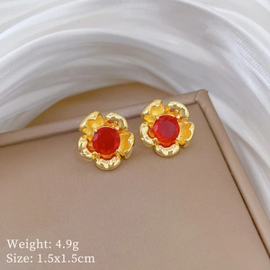 Detailed view of gold flower stud earrings with red gemstones on a display tray