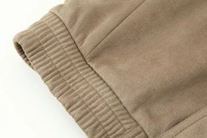 Detail of dark khaki suede jacket featuring ribbed elastic hem and fine textured fabric