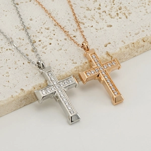 Close-up of stainless steel cross pendant necklaces with zircon inlay on travertine stone