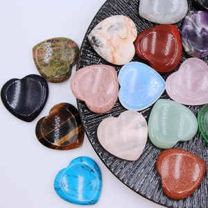 Polished 40mm natural crystal heart stones in various gemstones on a textured black plate
