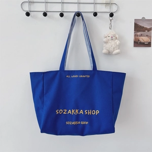 Detail der blauen Canvas-Tasche mit Goldstickerei und blau gestreiftem Innenfutter