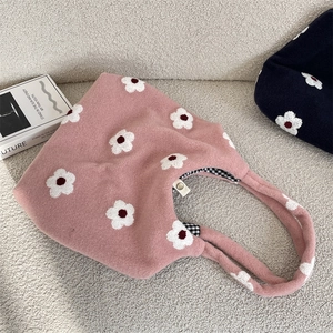 Close-up of pink plush tote bag showing daisy embroidery and black white checkered lining