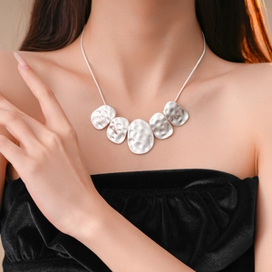 Chic silver hammered metal necklace with irregular oval pendants on a model's collarbone