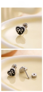 Detailed view of silver heart stud earrings with black enamel and a bow tie accent