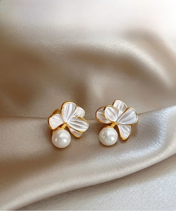 Détails de boucles d'oreilles fleurs et perles élégantes sur satin doré, style chic