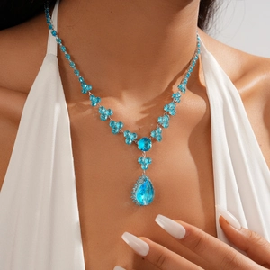 Detail of luxury teardrop blue zircon necklace on model with flower chain link