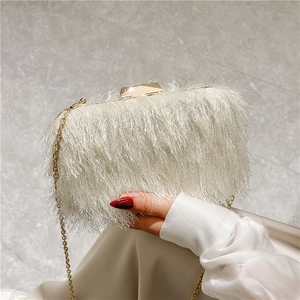 Detailed close-up of white feather evening bag with gold chain and metal clasp
