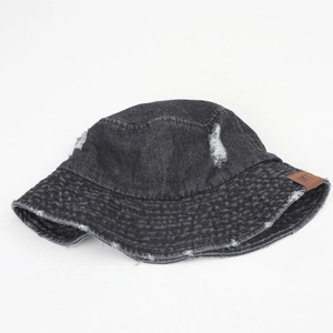 Détails d'un chapeau bob en jean noir délavé avec déchirures et étiquette en cuir marron