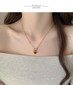 Close-up of 18k gold plated necklace with red heart pendant and enamel charms on collarbone