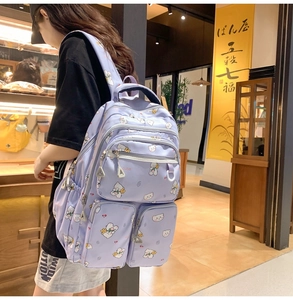 Close-up of a purple backpack with cute bear prints on a model in a warm bakery setting