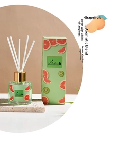 Close-up of grapefruit reed diffuser set with glass bottle and white sticks in a gift box