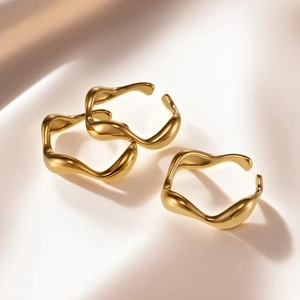 Close-up of golden wavy rings on silk fabric showing organic curved design and metal luster