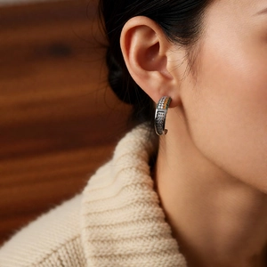 Detailed view of a vintage silver hoop earring set with zircon on model's ear