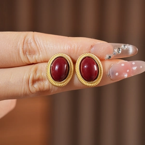 Detail of vintage gold oval earrings with deep red gemstones on a hand model