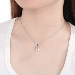 Close-up of a silver bow knot pearl pendant necklace worn by a female model