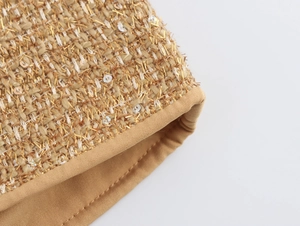 Detailed macro view of woven tweed fabric with metallic gold thread and sequins