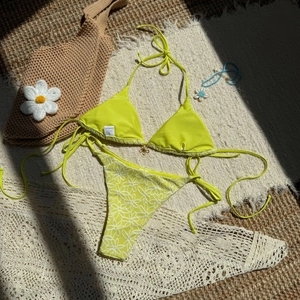 Detailed flat lay of neon green bikini set with daisy print and sun hat background