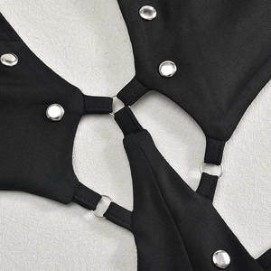 Détail de combinaison évasée noire avec rivets argentés et anneaux métalliques