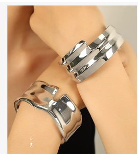 Macro shot of silver wide wave open cuff bracelets with polished mirror finish on model