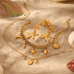 Golden ocean jewelry set with starfish pendants displayed on a sandy beach background