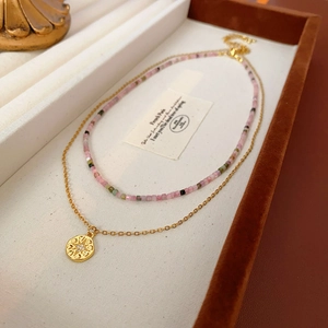 Détail du collier à perles colorées superposées avec chaîne dorée et pendentif soleil