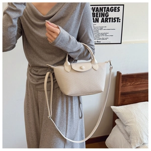 Detail of beige woven texture crossbody bag with leather handle and round snap button