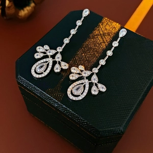 Detailed view of silver zircon drop earrings on a green textured jewelry gift box