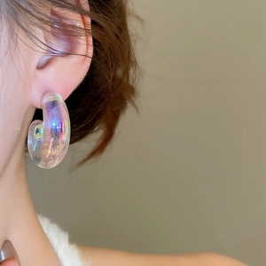 Close-up of a model wearing iridescent C-shaped acrylic earrings with a glossy aurora finish