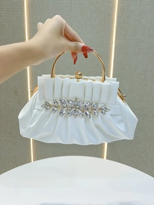 Detailed view of a white pleated evening clutch featuring marquise crystal floral accents