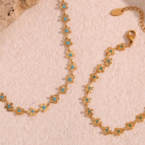 Macro detail of 18K gold plated necklace with small blue turquoise floral motifs