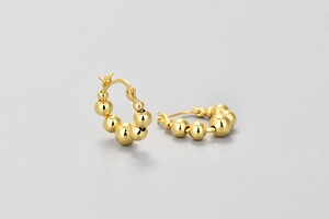 Macro detail of gold beaded earrings featuring the S925 hallmark for quality assurance