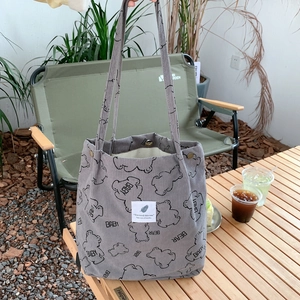 Detailed texture of grey corduroy tote bag featuring cute bear print on camping table