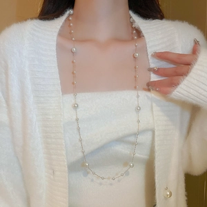 Detailed view of long gold-plated necklace with irregular pearls on elegant model
